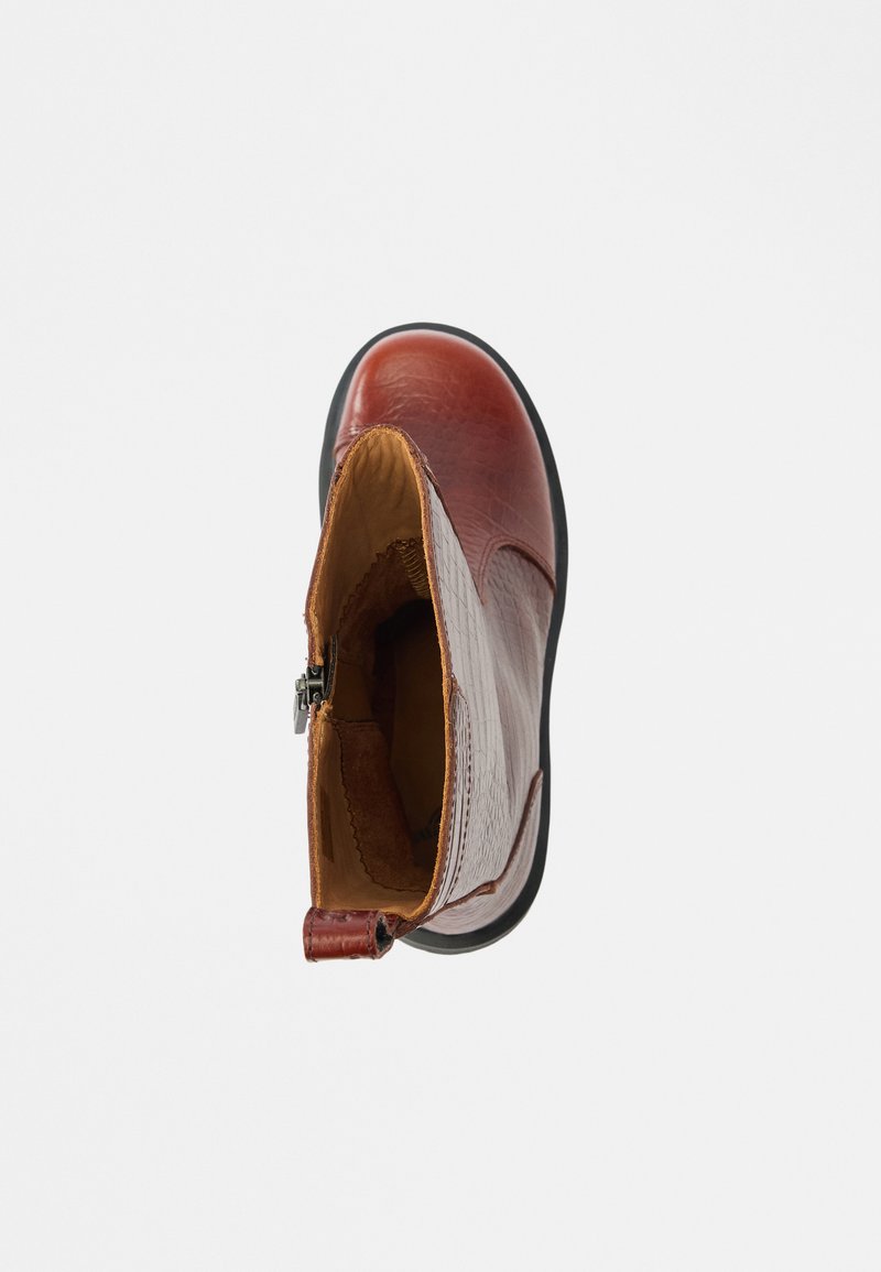 Leather ankle boot in reddish-brown with a textured finish, contrasting tan lining, zipper closure, and a sturdy black rubber sole.