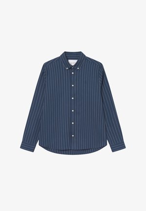 Tummansininen nappivaatteinen paita, jossa on valkoisia pystysuoria raitoja, terävä kaulus ja pitkät hihat. Paita on pyöristetyn helman ja pienen rintataskun kanssa.