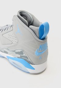 Pantofi sport înalt gri cu accente albastre, având un superior neted, limbă texturată și amortizare vizibilă în călcâi.