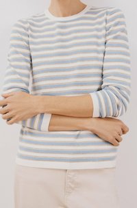 Sweter w paski w jasnoniebieskim, białym i złotym kolorze. Okrągły dekolt, długie rękawy i ściągacze. Miękka faktura, casualowy styl.