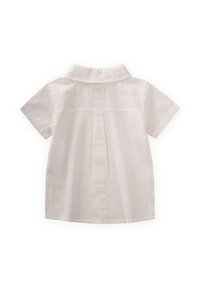Camicia bianca a maniche corte realizzata in tessuto testurizzato. Presenta un colletto classico, una piega sul retro e una chiusura a bottone al collo.