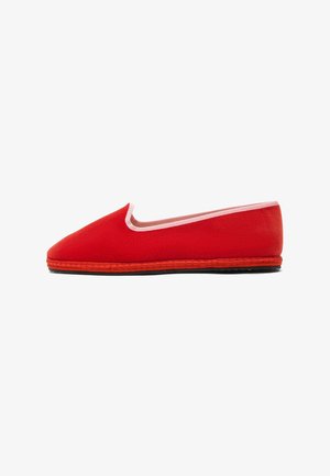 Botte slip-on en toile rouge avec une semelle en caoutchouc flexible, présentant une bordure contrastante rose clair le long du col et une texture lisse.
