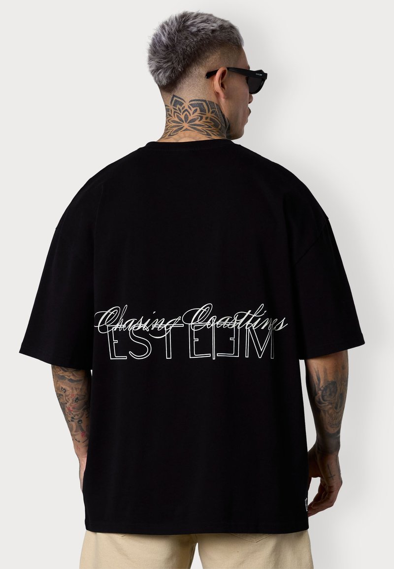 T-shirt noir oversize avec du texte en écriture cursive et en caractères d'imprimerie blanche dans le dos. Fabriqué en coton doux, avec une coupe décontractée et des manches courtes.