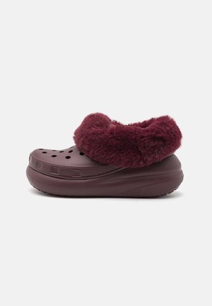 Zoccolo slip-on color granata con perforazioni e una fodera spessa, morbida e pelosa intorno alla caviglia.