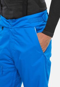 Blaue Outdoor-Hosen aus leichtem, strapazierfähigem Material. Verfügen über zwei seitliche Taschen, eine mit Reißverschluss und einen sicheren Bund mit Knopfverschluss.