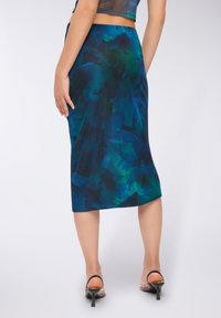 Spódnica A-line o długości midi w ciemnoniebieskim kolorze z zielonymi abstrakcyjnymi wzorami. Wykonana z gładkiego materiału, ma dopasowany pas i lekki połysk.