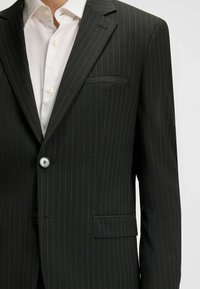 Black pinstripe blazer with a single button closure, notched lapels, and a chest pocket. Fabric has a smooth texture and subtle shine.
