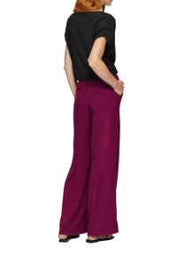 Brede broek in levendig fuchsia, gemaakt van lichtgewicht stof. Gecombineerd met een zwart gemêleerd topje, gezien vanaf de achterkant, met zichtbare achterzakken.