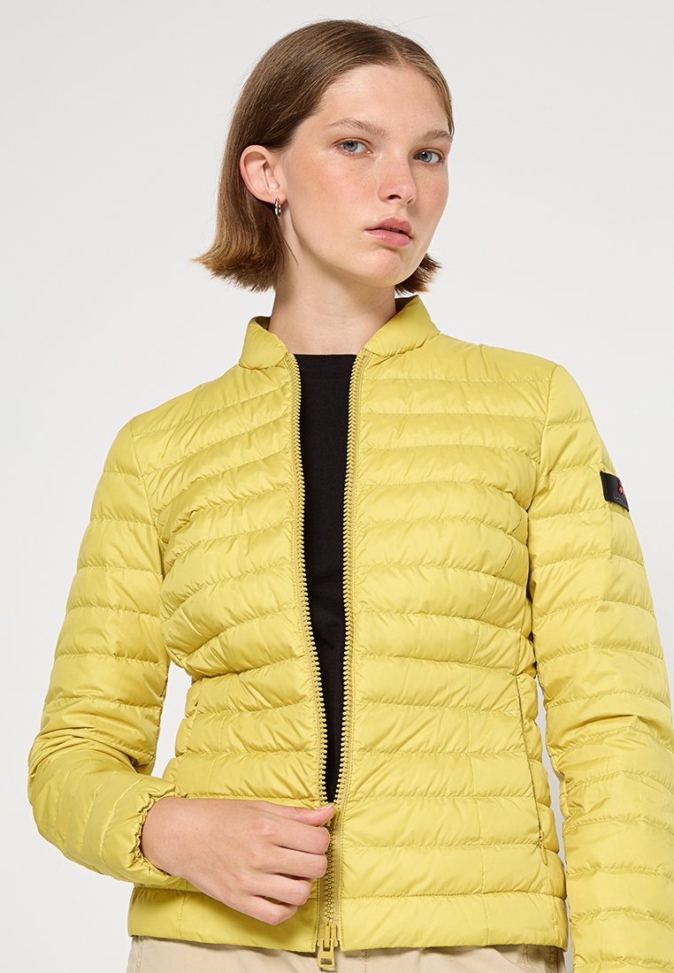 Gelbe gepolsterte Jacke mit Stehkragen, Reißverschluss und strukturiertem Nähen. Die Jacke verfügt über ein Logo-Patch am linken Arm.