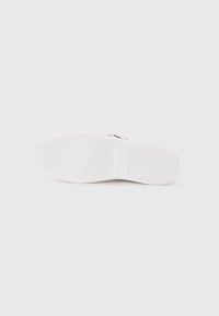 Suola di sneaker bianca con una superficie in gomma testurizzata, caratterizzata da scanalature orizzontali e minimi accenti. Design pulito senza dettagli aggiuntivi.