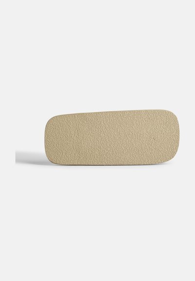 Beige pohjalliset, joissa on teksturoitu pinta, pyöristetyt reunat ja litteä muoto. Materiaali näyttää kestävältä ja mukavalta, sopii jalkineisiin.