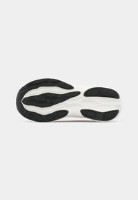 Semelle d'une basket avec des coussinets de traction en caoutchouc noir et une semelle intermédiaire blanche, montrant un motif de crampons détaillé pour l'adhérence et le soutien.