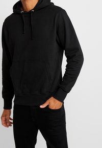 Schwarzer Pullover-Hoodie aus weichem Material, mit einer Front-Kängurutasche, verstellbarem Kordelzug und gerippten Bündchen und Saum.