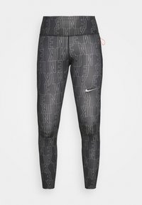 Czarne legginsy Nike z wysokim stanem, z wzorem w białe kontury tekstu na całej powierzchni i małym białym logotypem Nike na udzie.