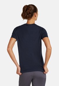 Camiseta de manga corta azul marino, textura suave, escote redondeado, diseño ajustado, sin patrones ni acentos visibles, vista desde la parte de atrás.