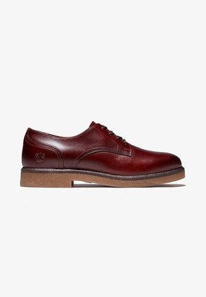 Chaussure habillée en cuir rouge foncé à lacets, finition lisse, bout arrondi, détails cousus et semelle en caoutchouc marron clair sur fond blanc.