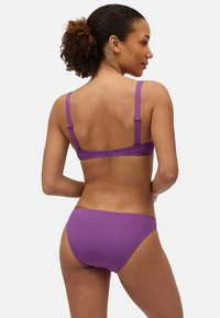 Conjunto de bikini púrpura con tela texturizada, tirantes ajustables y un diseño simple. La parte superior cuenta con un cierre en la parte posterior para un ajuste seguro.