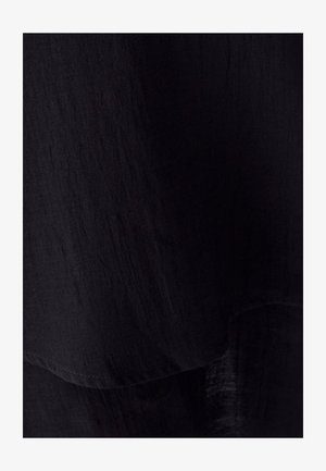 Čierna textúrovaná tkanina so mierne pokrčeným povrchom, s mäkkými záhybmi a zakriveným lemovaním, vyžarujúca ľahký a vzdušný vzhľad.