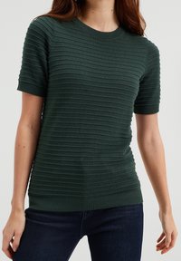 Grön ribbad stickad tröja med korta ärmar, rund halsringning och texturerade horisontella ränder. Mjuk material med figurnära design.