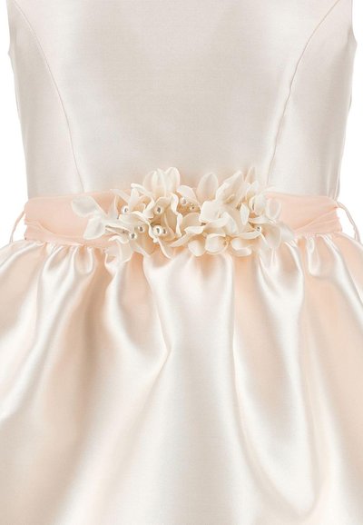 Vestido de satén color crema con una banda melocotón en la cintura adornada con flores de tela y pequeñas decoraciones de perlas.