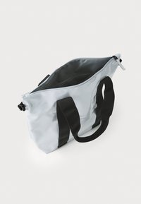 Lys grå vanntett bag med svarte håndtak og detaljer, med glidelås og romslig innvendig plass med en jevn tekstur.