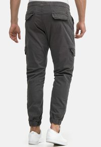 Gray cargo pants with elastic cuffs, side pockets, and a relaxed fit. Made from durable fabric, featuring a smooth texture and light sheen.