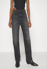 Jeans rectos negros de talle alto en denim con una textura suave. Presentan un diseño clásico de cinco bolsillos y detalles en hardware plateado.