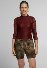 Bordeaux Spitzenoberteil mit Dreiviertelärmeln, kombiniert mit braunen Shorts mit floraler Stickerei und dekorativen Nähten.