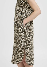 Abito con stampa leopardata, caratterizzato da maniche corte, tasche laterali, taglio al ginocchio e un'apertura a spacco sull'orlo, realizzato in tessuto morbido.