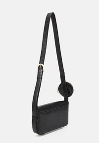Borsa nera in ecopelle con texture cocodrillo, dotata di una lunga tracolla, un portamonete rotondo rimovibile e una forma rettangolare strutturata.