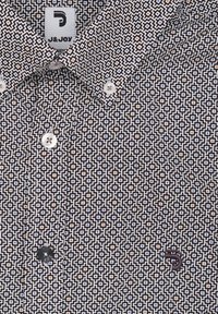 Korte mouwen shirt met een geometrisch patroon in zwart, wit en blauw, voorzien van een kraag en een geborduurd logo op de borst. De knopen zijn wit.