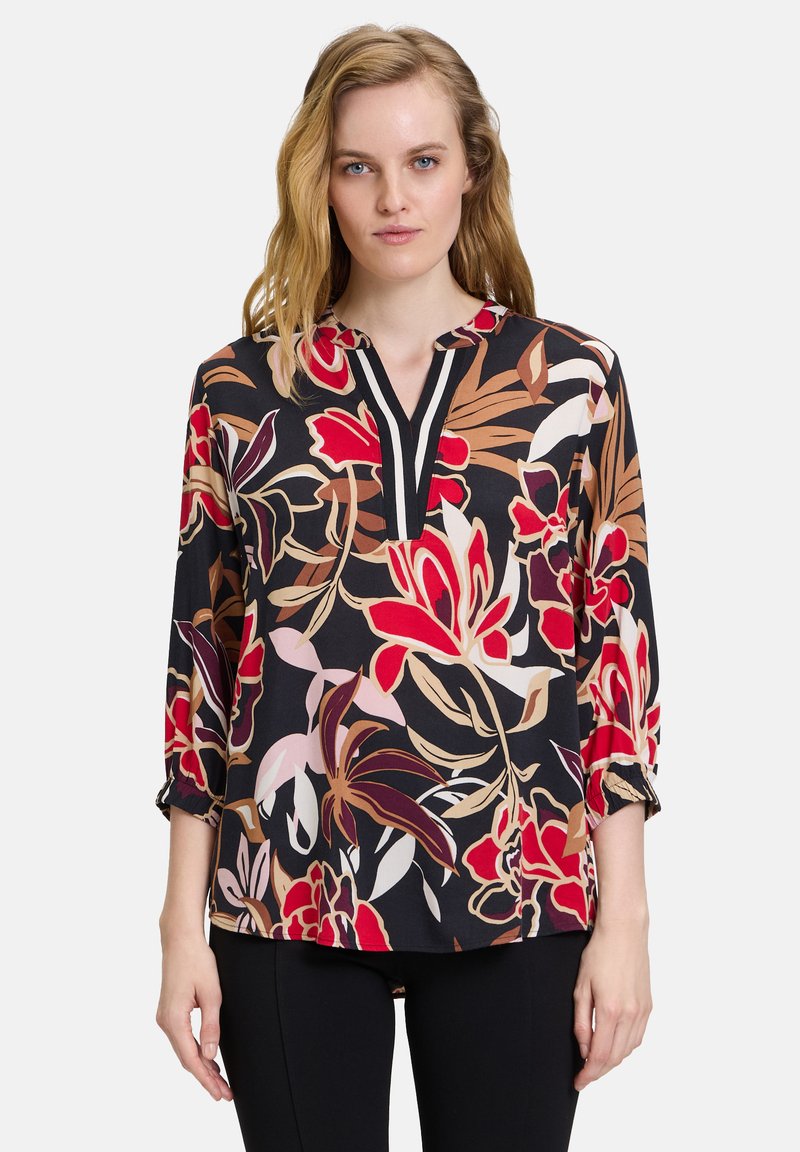 Bloes met bloemenprint in gedurfde rood-, roze- en bruintinten op een zwarte achtergrond, met een V-hals, driekwart mouwen en gathered cuffs.