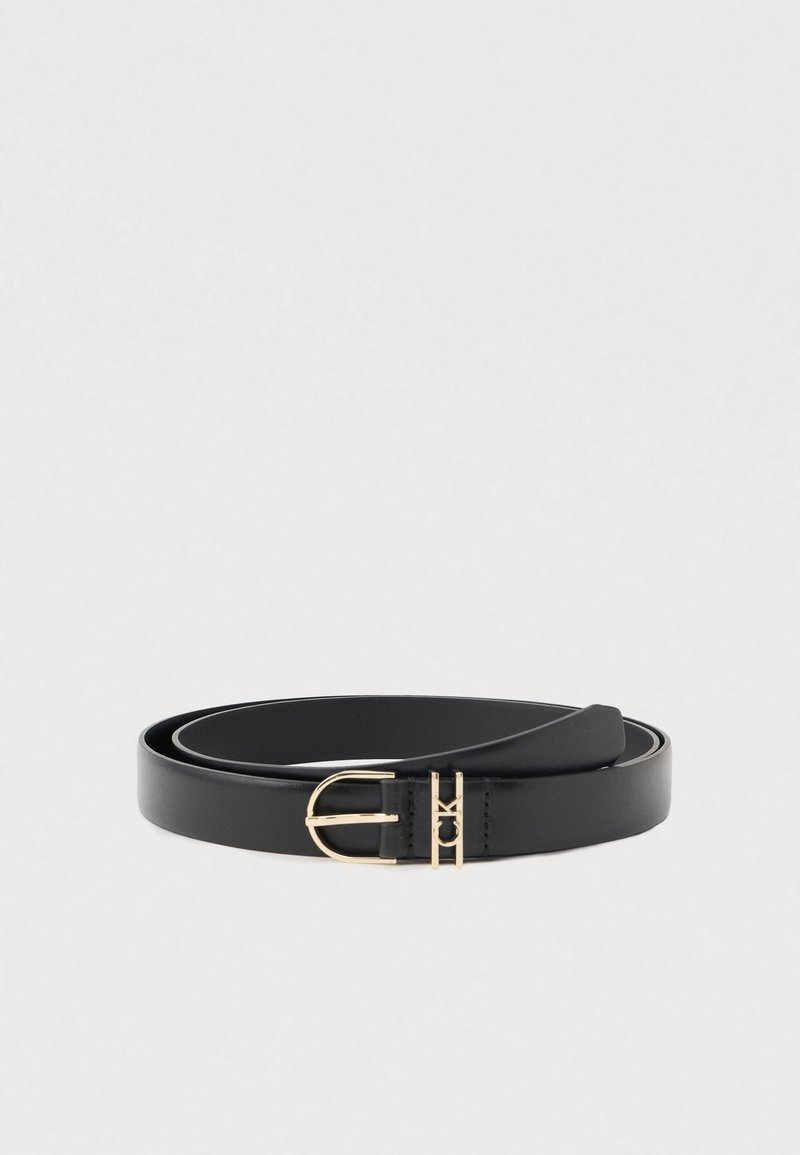 Ceinture en cuir noir roulée avec une boucle arrondie dorée et détail du logo CK sur un fond clair uni.