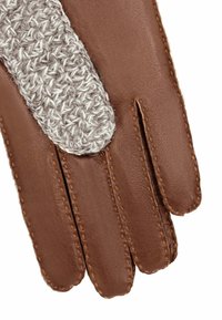 Gant en cuir marron avec un accent tricoté gris texturé sur le doigt du milieu. Couture visible le long des bords. Quatre doigts allongés.