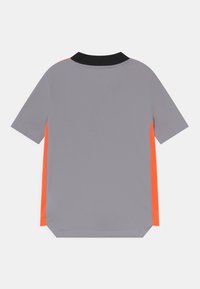 Harmaa lyhythihainen paita mustalla kauluksella ja kirkkaan oransseilla sivupaneeleilla, esitetty takaa, valkoista taustaa vasten.