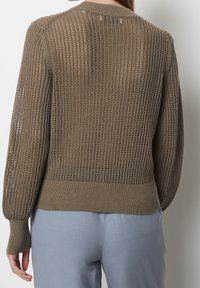 Brązowy sweter z dzianiny, z otwartym wzorem siatkowym, ściągaczami na rękawach i dole, oraz okrągłym dekoltem. Tył ma teksturowane wykończenie.