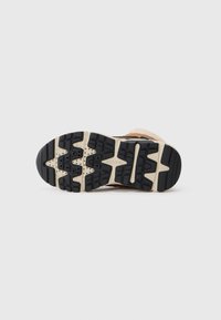 Zool van een bruine laars met een zwart en beige loopvlakpatroon, met de merknaam Geox op een simpele witte achtergrond.