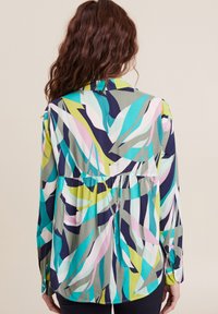 Langarmhemd aus leichtem Stoff mit einem mehrfarbigen abstrakten Muster in Grün, Blau, Pink und Navy. Taillierte Raffung.