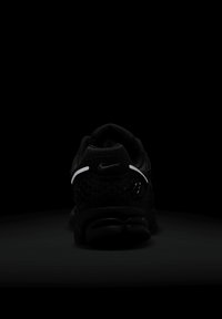 Juodos Nike sportbačiai su tekstūruotu paviršiumi, tinkliniais elementais ir atšvaitu juostos prie kulno. Pasižymi ryškiu paminkštintu padu.