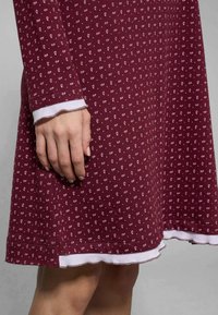 Abito borgogna con una stampa paisley bianca, caratterizzato da maniche lunghe, orlo scallop e bordi bianchi a strati sui polsini e sull'orlo.