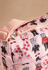 Vadderad rosa väska med mönster av tecknade djur, försett med ett blixtlås upptill med en ljusrosa dragflik och ett texturerat band.