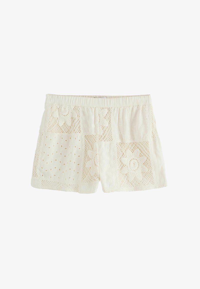 Shorts en dentelle blanche avec motifs floraux, découpes complexes et taille élastique froncée. Tissu léger avec détails texturés.