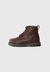 Bota de tobillo de cuero marrón con acabado texturizado, puntera redonda y cordones negros. Cuenta con una suela resistente con patrón de banda de rodadura y una lengüeta.