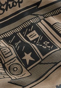 Beige fabric featuring a black illustrative design of a shop front, with windows, signs, stars, and various lines and patterns.