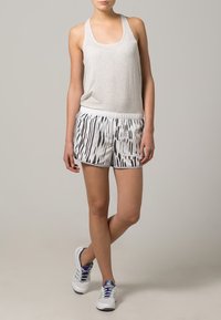 Gray tank top paired with white shorts featuring black vertical stripes. White athletic shoes with purple accents.