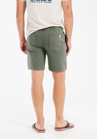 Olijfgroene shorts met een rechte snit, met twee achterzakken en een tailleband. Draag ze met een casual, lichtgekleurd t-shirt en sandalen.