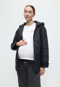 Μαύρο μπουφάν με καπιτονέ, κουκούλα, κουμπιά πάτου και πλαϊνές τσέπες, φορεμένο πάνω από λευκό πουκάμισο και σκουρόχρωμη τζιν φούστα, με λεία υφή.