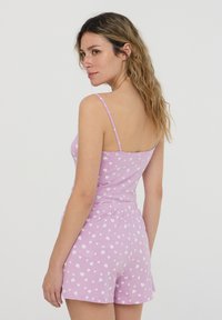 Completo da notte rosa composto da un top con spalline sottili e pantaloncini, entrambi con un motivo a cuori bianchi su un morbido cotone.