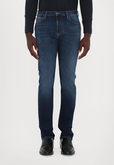 Jeans in denim blu scuro con una vestibilità slim, dotati di cinque tasche, cuciture sottili e una chiusura con bottone classica sulla cintura.