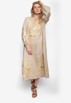 Lniana sukienka w beżowym kolorze z złotym kwiatowym haftem, długimi bufkami oraz akcentami z chwostami. Okrągły dekolt i długość sięgająca kostek.
